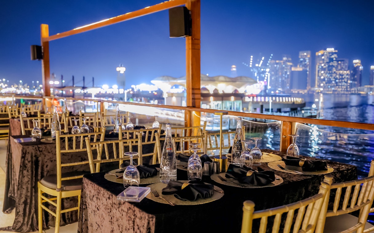 Dining setup on Dubai Canal Dinner Cruise with city skyline in the background.