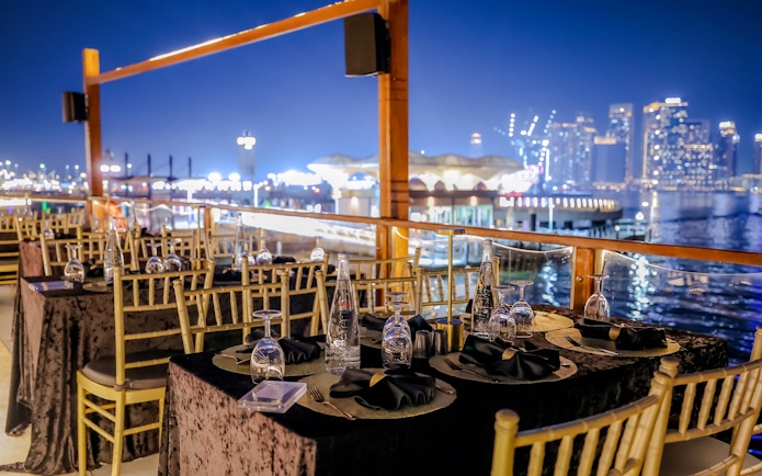 Dining setup on Dubai Canal Dinner Cruise with city skyline in the background.