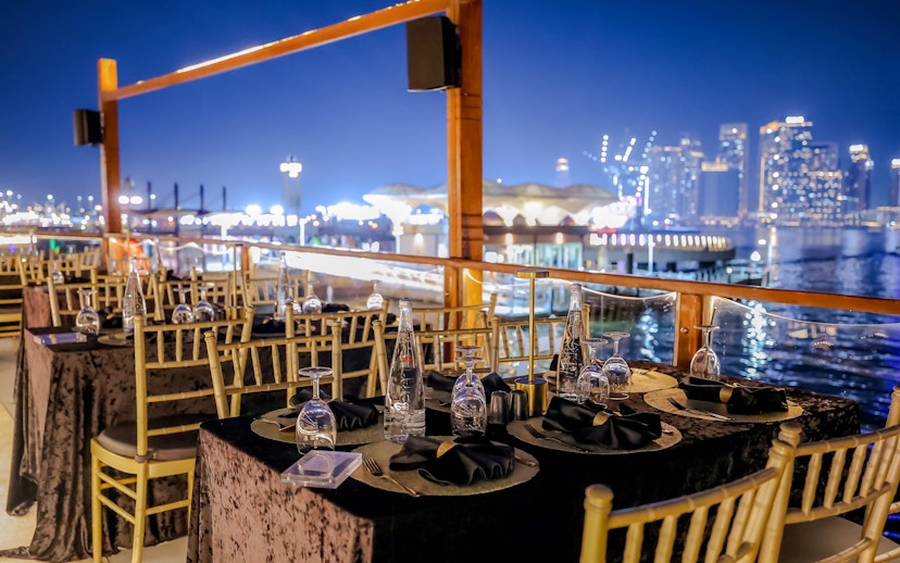 Dining setup on Dubai Canal Dinner Cruise with city skyline in the background.