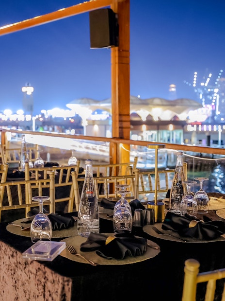 Dining setup on Dubai Canal Dinner Cruise with city skyline in the background.