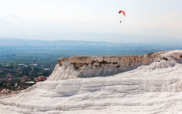 Tandem paragliding over Pamukkale's travertine terraces, Turkey.
