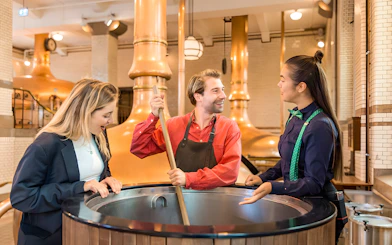 Tourists brewing beer at Heineken Experience in Amsterdam brewery.