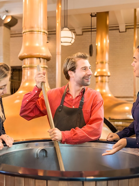 Tourists brewing beer at Heineken Experience in Amsterdam brewery.
