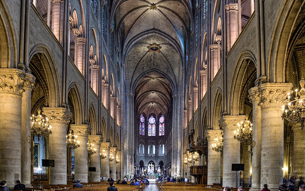Nave of Notre Dame Cathedral with stained glass windows and vaulted ceilings.