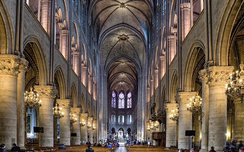 Nave of Notre Dame Cathedral with stained glass windows and vaulted ceilings.