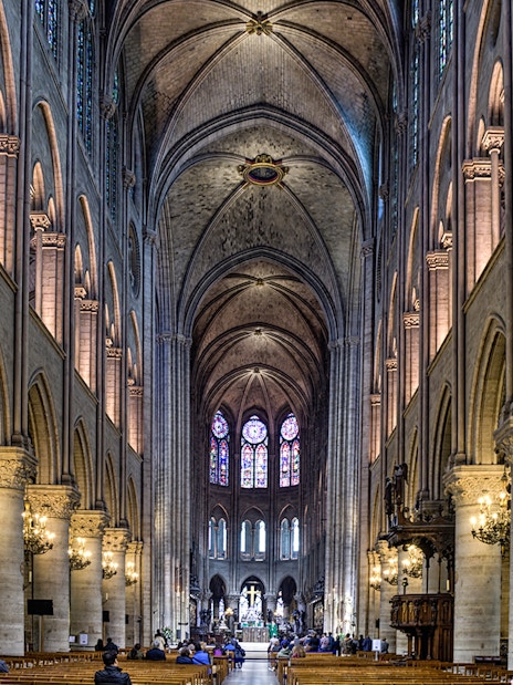 Nave of Notre Dame Cathedral with stained glass windows and vaulted ceilings.