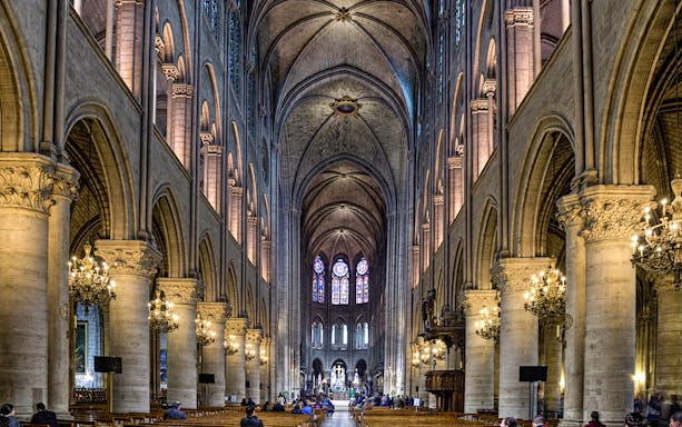 Nave of Notre Dame Cathedral with stained glass windows and vaulted ceilings.