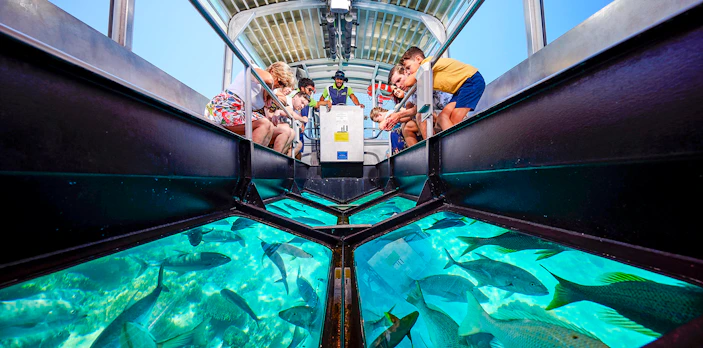 Tourists on a glass bottom boat viewing coral and fish at Great Barrier Reef near Cairns, Australia.