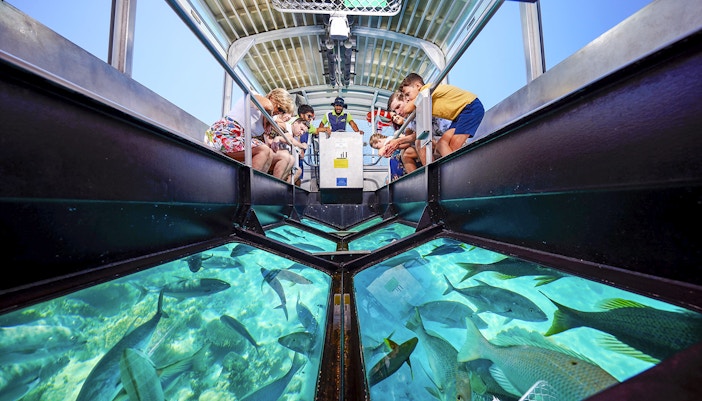 Tourists on a glass bottom boat viewing coral and marine life at Great Barrier Reef near Cairns, Australia.