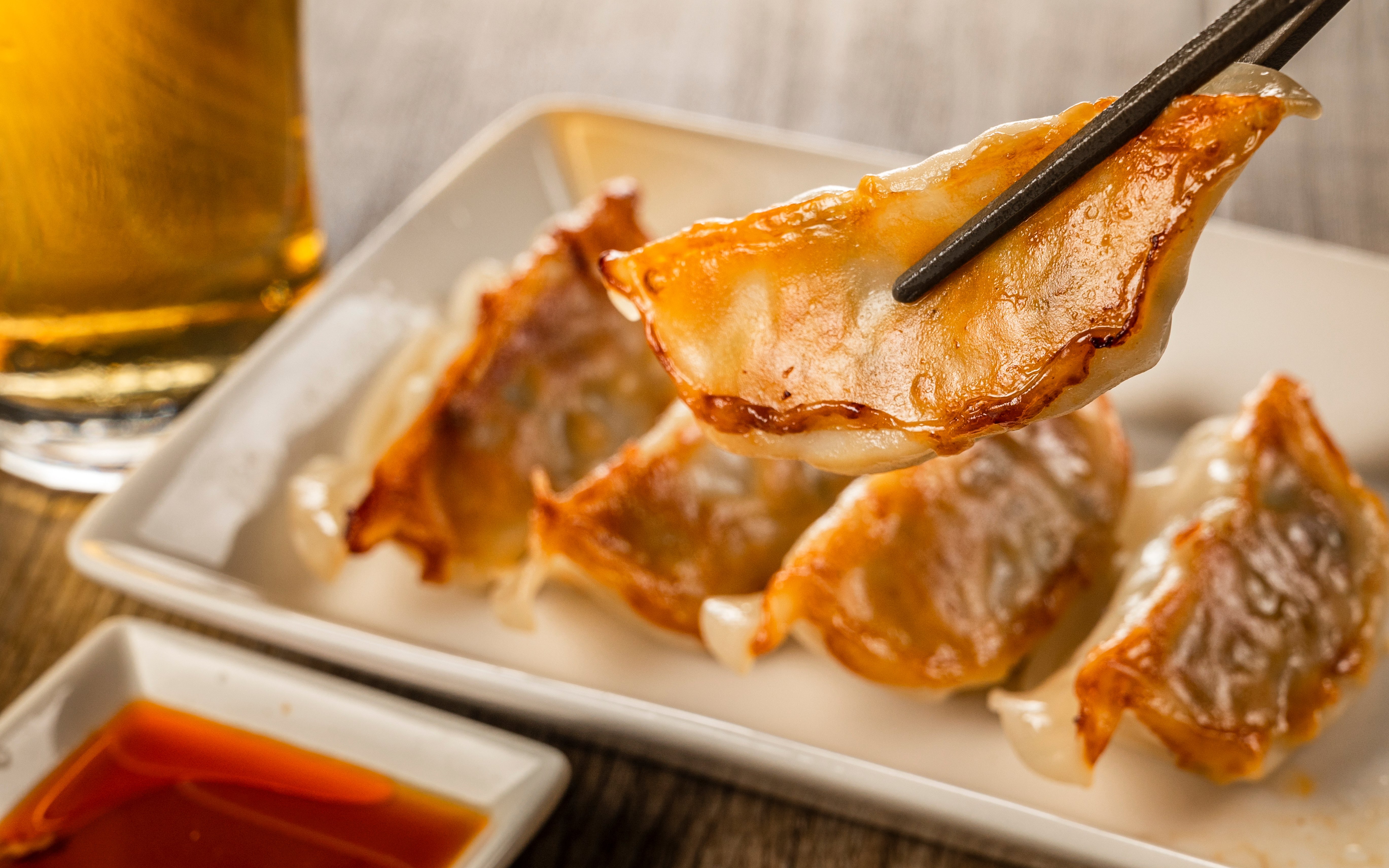 Gyoza dumplings on a plate with chopsticks and dipping sauce.
