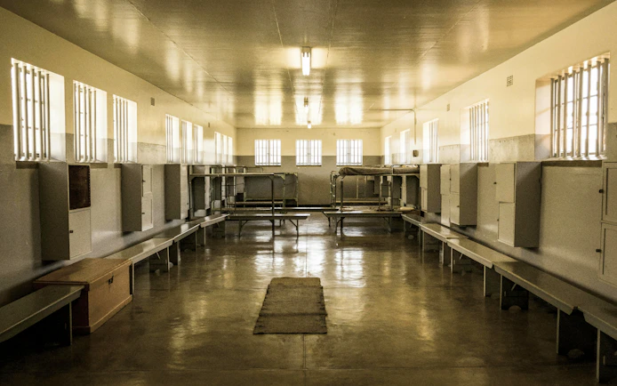 Robben Island prison cell block interior with barred windows and bunk beds.