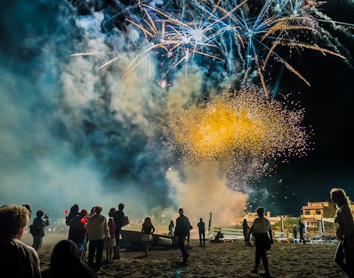 Crowd watching Ferragosto fireworks on a beach at night.