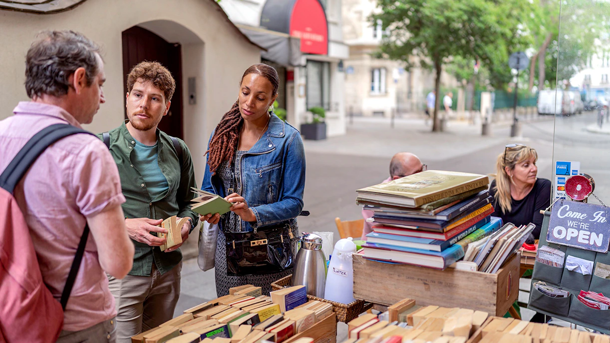 Visitors browsing books at an outdoor stall in Paris's Latin Quarter.