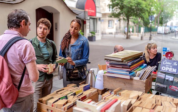Visitors browsing books at an outdoor stall in Paris's Latin Quarter.