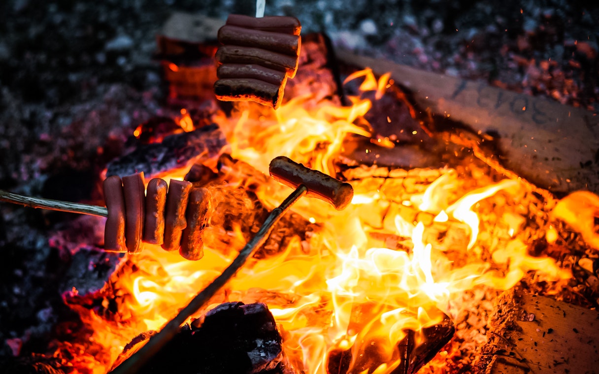 Roasting sausages over a campfire under the Northern Lights.