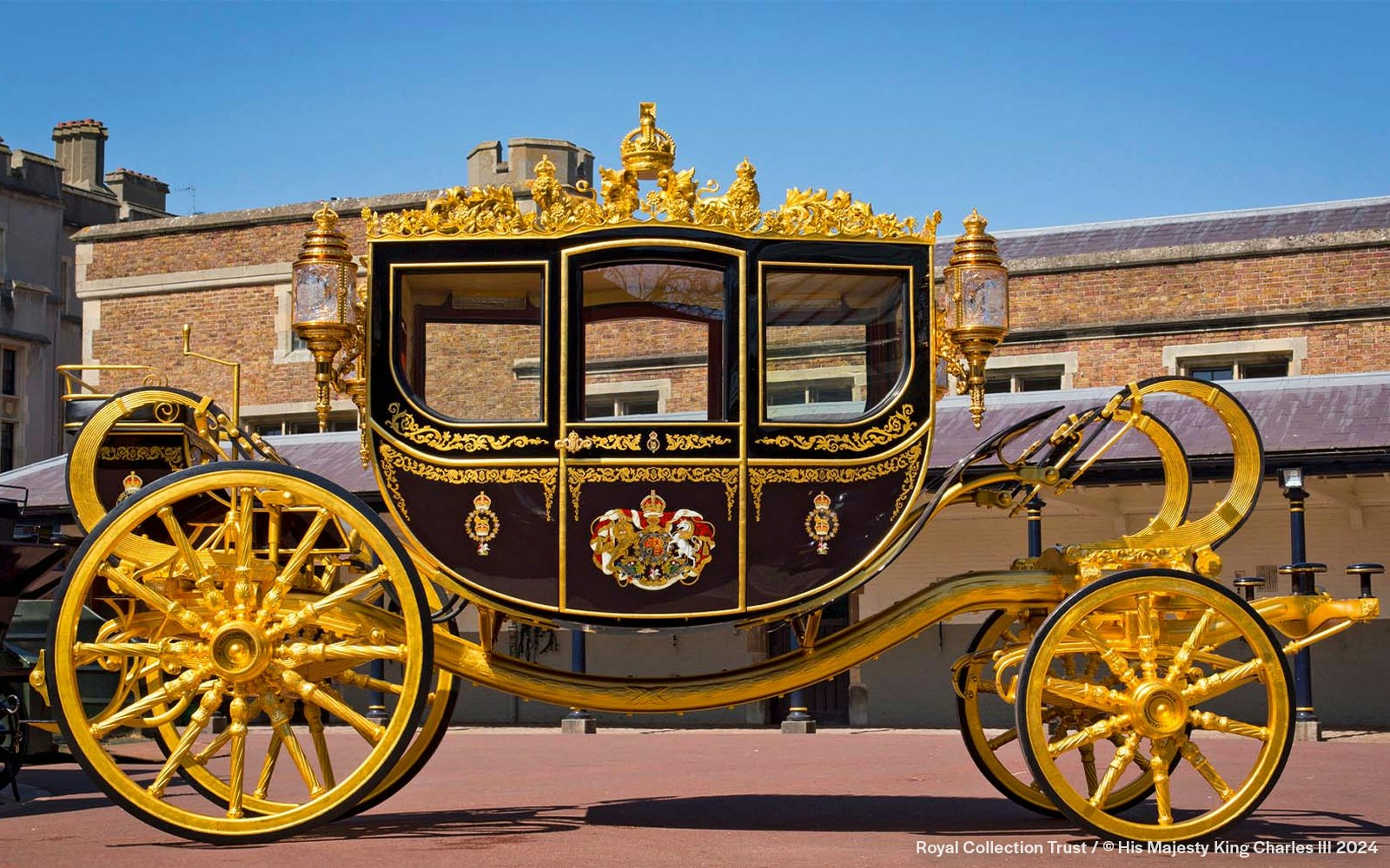 Golden royal carriage at Buckingham Palace courtyard.