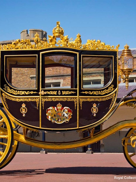 Golden royal carriage at Buckingham Palace courtyard.