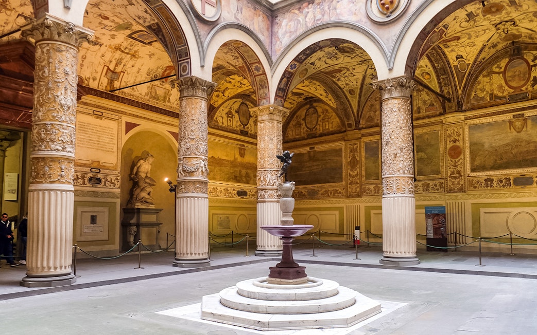 Courtyard of the Palazzo Vecchio with ornate columns and a central fountain in Florence, Italy.