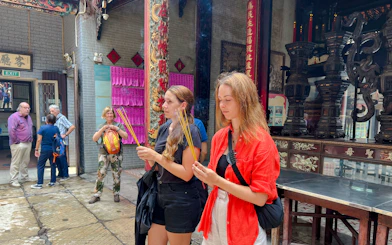 Visitors holding incense sticks at a temple in Ho Chi Minh City during Saigon Hidden Gems Day Tour.