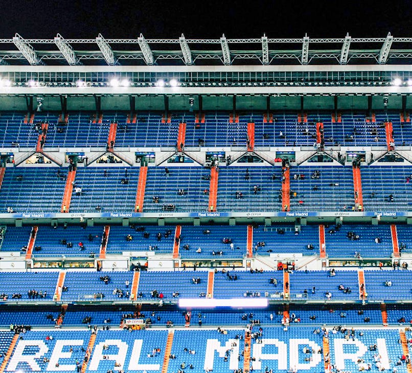 Bernabeu Stadium in Madrid with visitors exploring the iconic football field and seating areas.
