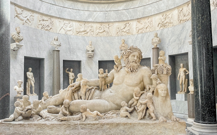 Statue of river god Oceanus surrounded by figures in Vatican Museums.