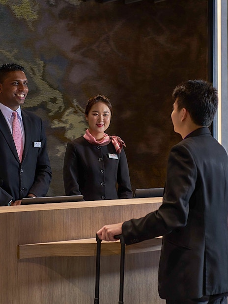 Reception desk at Plaza Premium First, Satellite Terminal, with staff assisting a traveler.