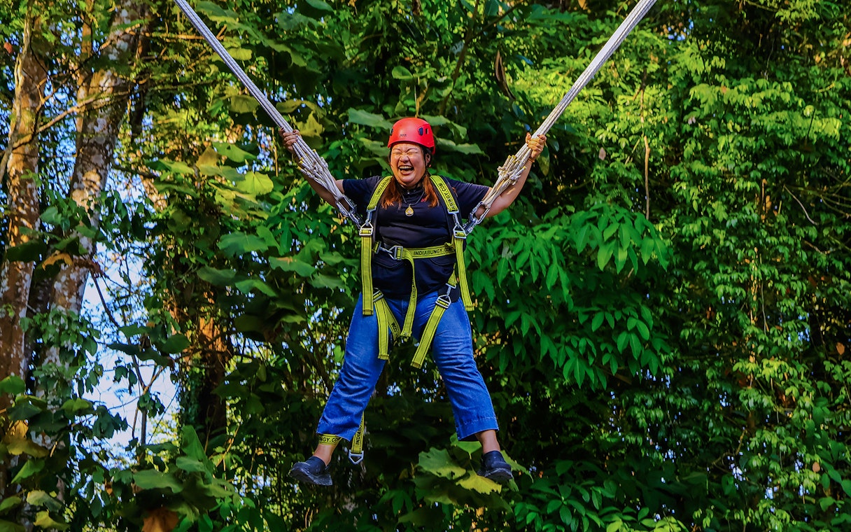 Person enjoying Slingshot Zipline at Hanuman World, surrounded by lush greenery.
