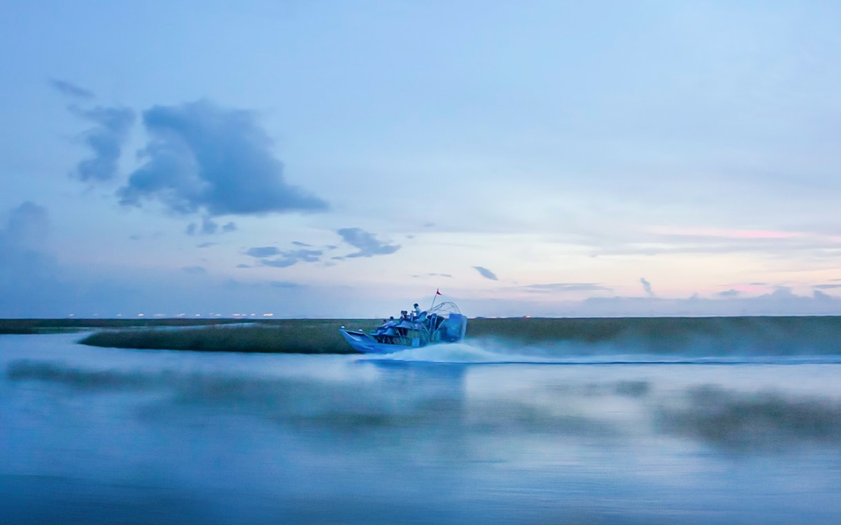 Airboat gliding through Everglades at dusk during night tour.