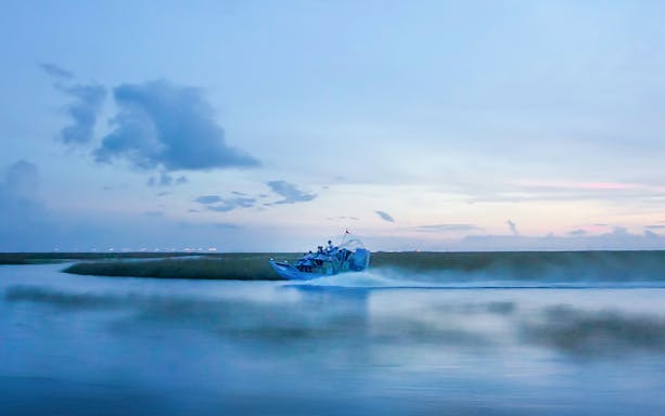 Airboat gliding through Everglades at dusk during night tour.