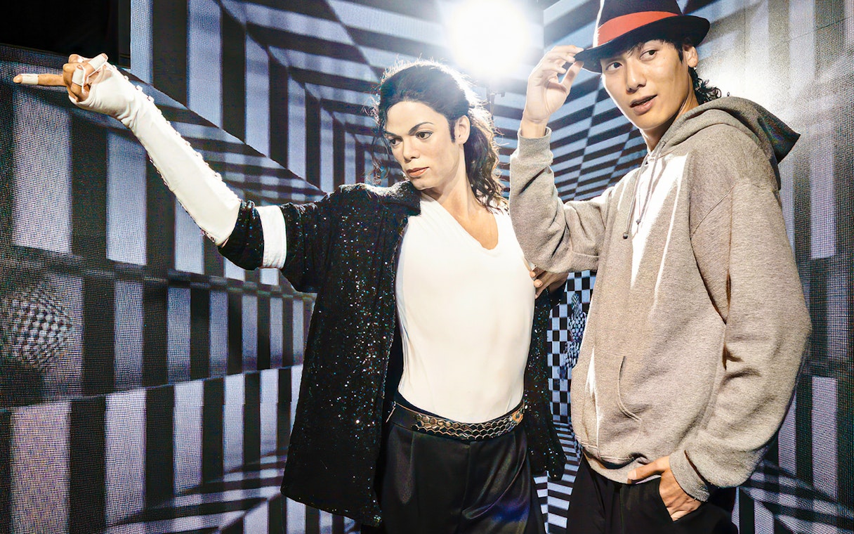 Wax figure at Madame Tussauds Tokyo with a visitor posing for a photo.
