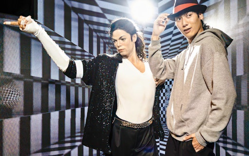 Wax figure at Madame Tussauds Tokyo with a visitor posing for a photo.