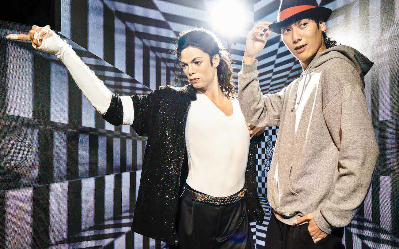 Wax figure at Madame Tussauds Tokyo with a visitor posing for a photo.