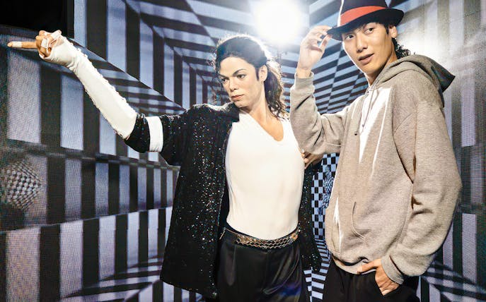 Wax figure at Madame Tussauds Tokyo with a visitor posing for a photo.