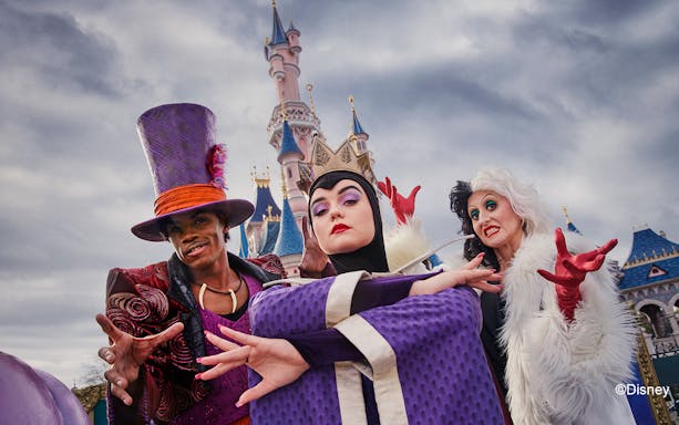 Disney villains posing in front of Sleeping Beauty Castle at Disneyland Paris during Halloween.