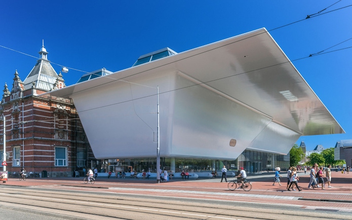 Stedelijk Museum exterior in Amsterdam with modern architecture and people walking nearby.