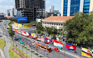 Open-top tour bus passing flags on a busy street in Ho Chi Minh City.