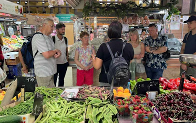 Group touring Valencia market for paella ingredients during cooking class.