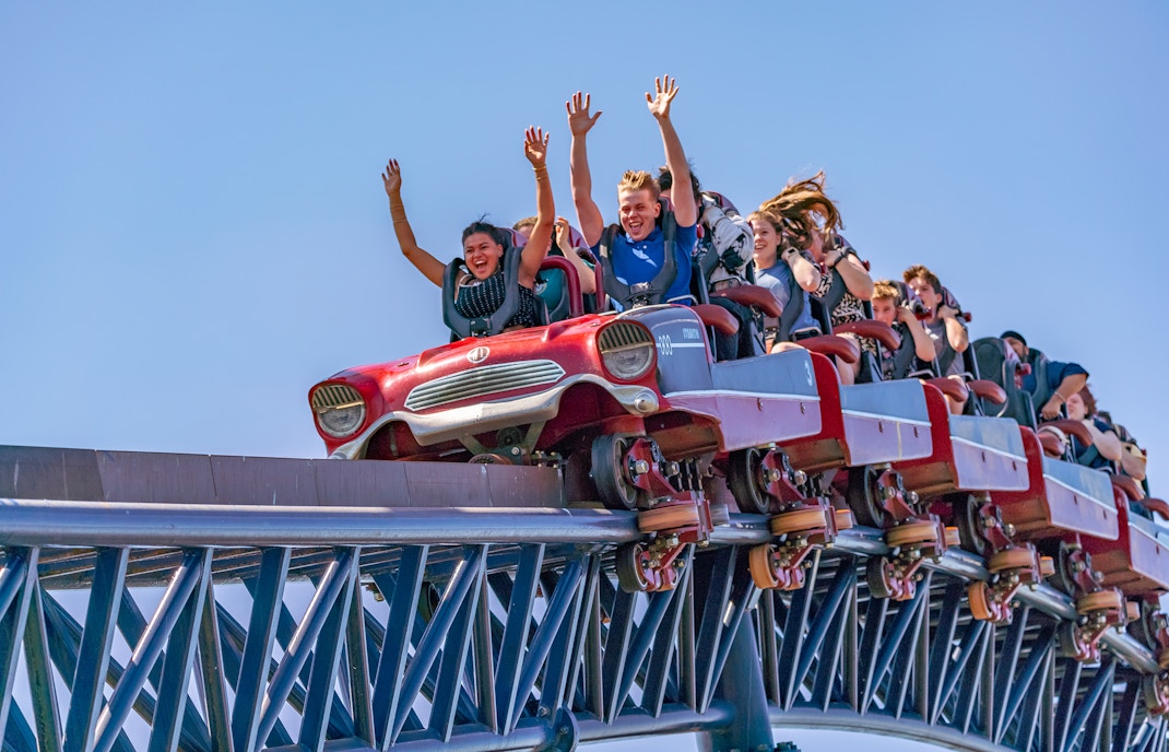 Thrilling ride on THE SWARM roller coaster at Thorpe Park Resort with riders' hands up.