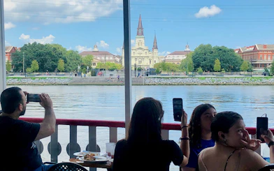 Sightseers on a riverboat capturing views of St. Louis Cathedral from the Mississippi River in New Orleans.