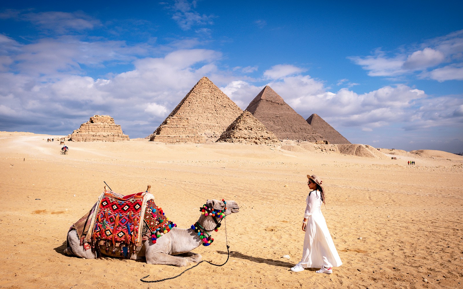 Woman with camel in front of the Pyramids of Giza, Egypt.
