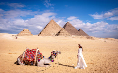 Woman with camel in front of the Pyramids of Giza, Egypt.