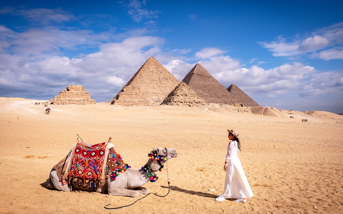 Woman with camel in front of the Pyramids of Giza, Egypt.