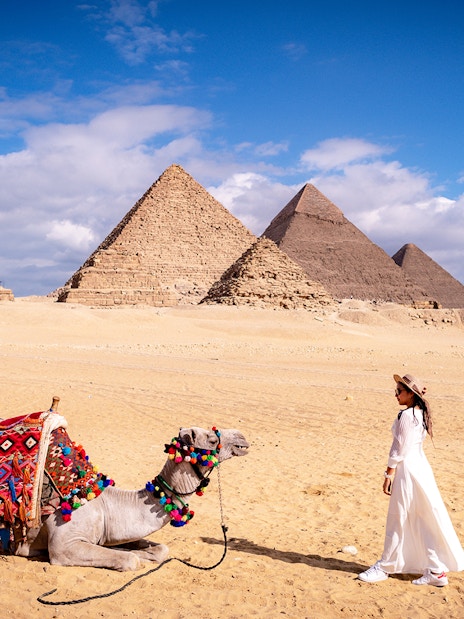 Woman with camel in front of the Pyramids of Giza, Egypt.