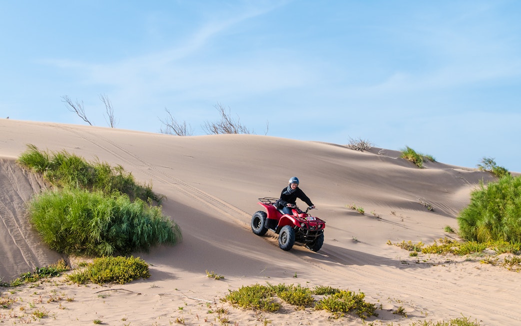 Person riding a quad bike on sand dunes in Agafay Desert.