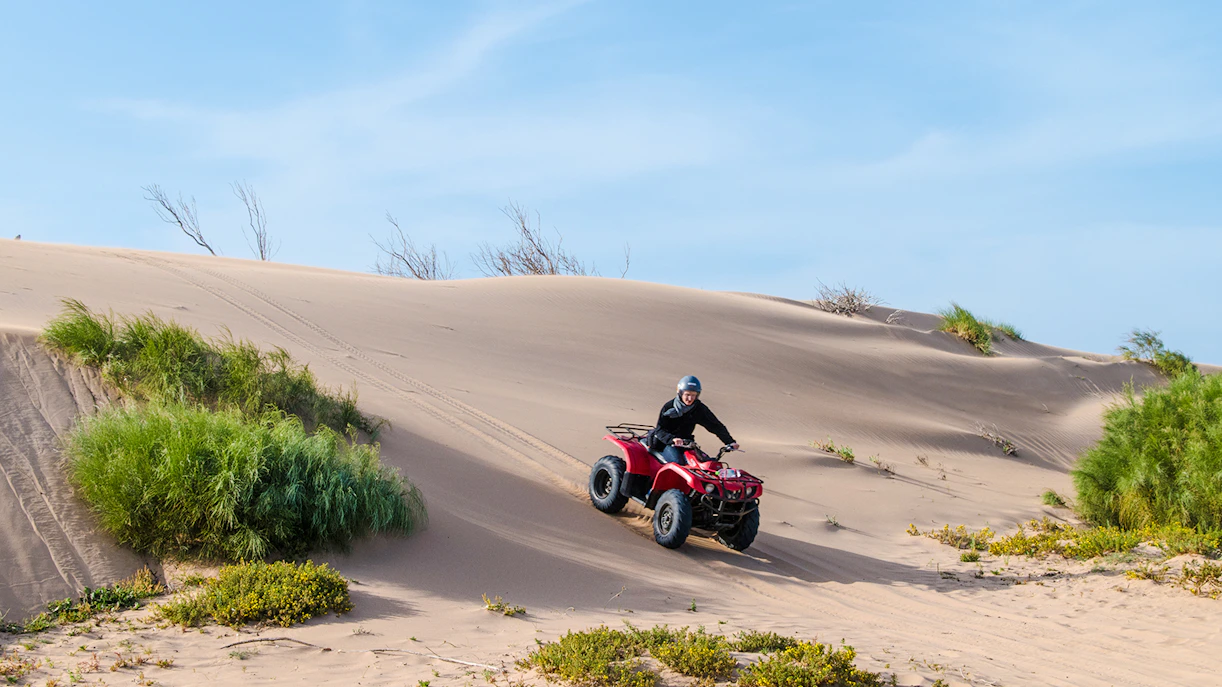 Person riding a quad bike on sand dunes in Agafay Desert.