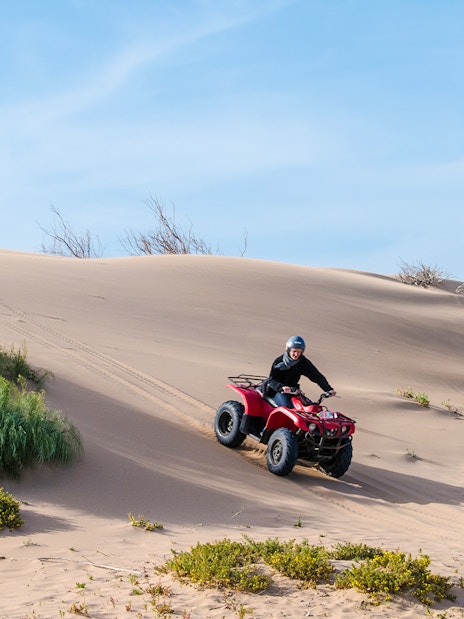 Person riding a quad bike on sand dunes in Agafay Desert.