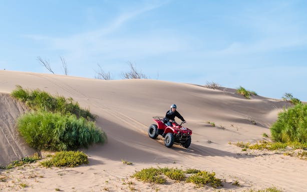 Person riding a quad bike on sand dunes in Agafay Desert.