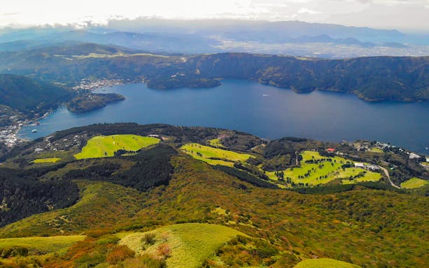 Aerial view of Lake Ashi with surrounding green hills and distant mountains in Japan.