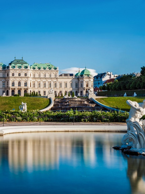 Statues in the gardens of Upper Belvedere Palace, Vienna, with palace in background.