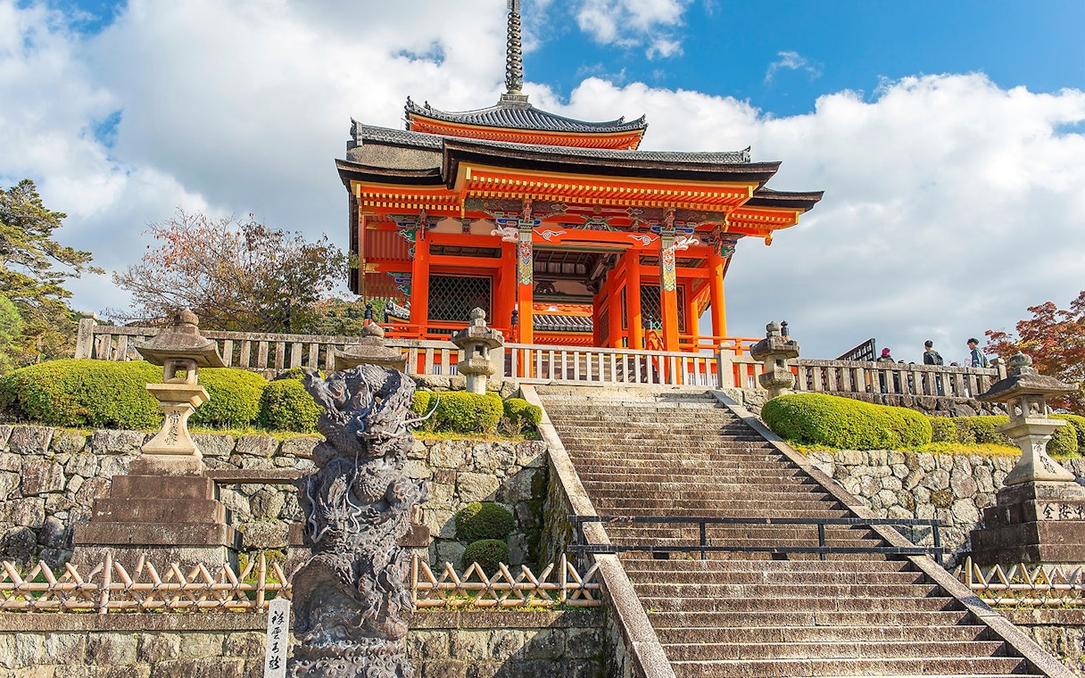 Kyoto temple with red pagoda and stone lanterns on a cultural tour.